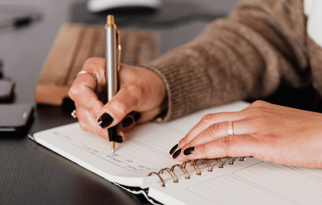 Lady writing in a note with pen